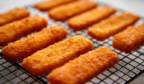 Rows of golden fried fresh fish fingers fillets